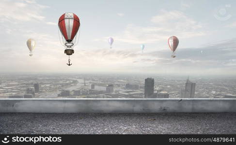 Aerostats flying over city. Colorful aerostats flying in clear sky above modern city