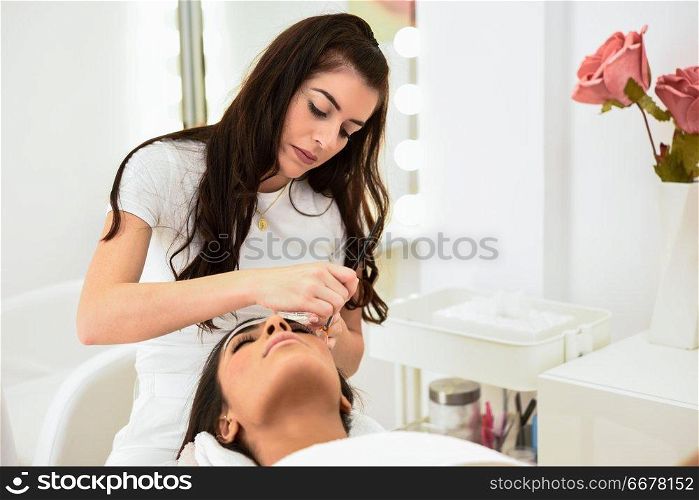 Aesthetics applying a mask to the face of a beautiful woman in modern wellness center. Beauty and Aesthetic concepts.. Aesthetics applying a mask to the face of a beautiful woman
