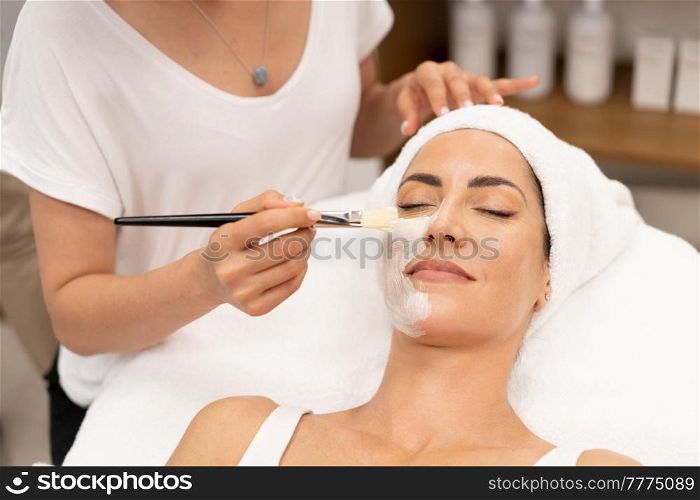 Aesthetics applying a mask to the face of a Middle-aged woman in modern wellness center. Beauty and Aesthetic concepts.. Aesthetics applying a mask to the face of a Middle-aged woman in modern wellness center.