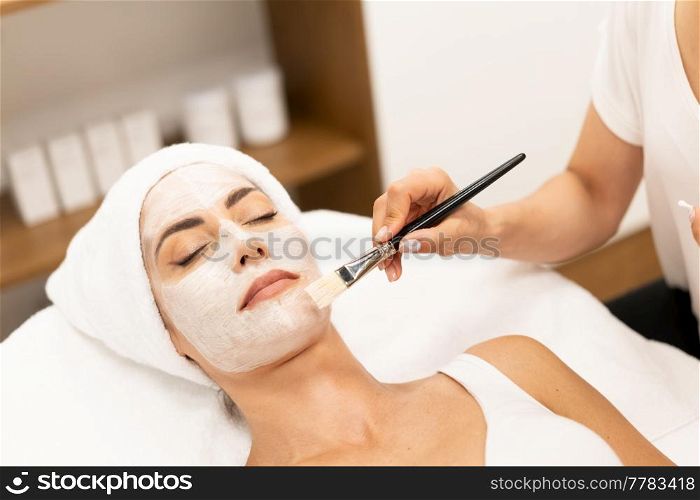 Aesthetics applying a mask to the face of a Middle-aged woman in modern wellness center. Beauty and Aesthetic concepts.. Aesthetics applying a mask to the face of a Middle-aged woman in modern wellness center.