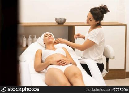 Aesthetics cleaning the skin to the face of a middle-aged woman in modern wellness center.. Beauty and Aesthetic concepts.. Aesthetics cleaning the skin to the face of a middle-aged woman in modern wellness center.