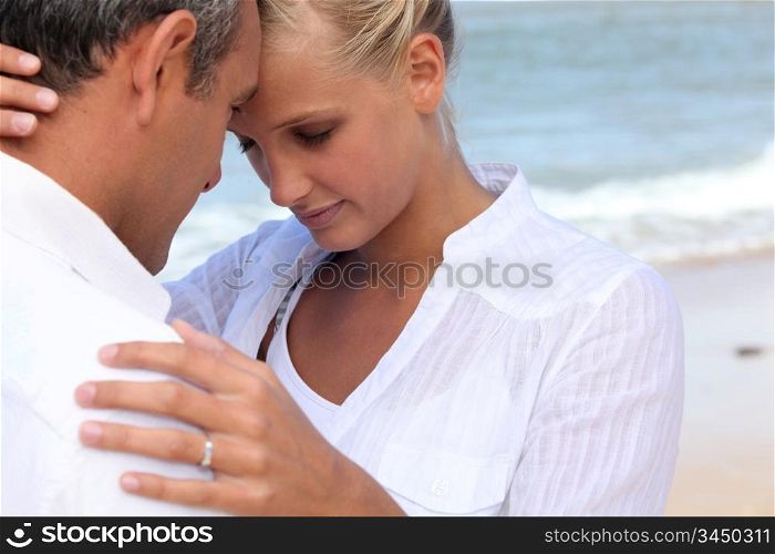 Affectionate couple dressed in white at the seaside