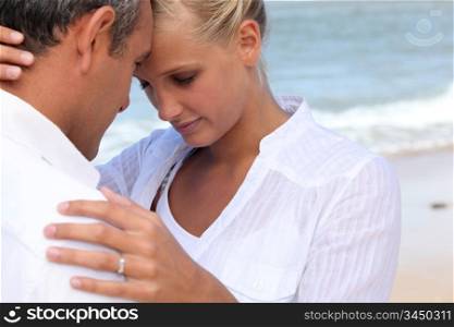 Affectionate couple dressed in white at the seaside