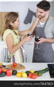 affectionate couple having a glass of wine while preparing meal