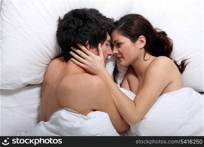 Affectionate couple kissing in bed