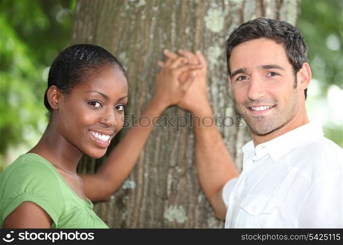 Affectionate couple stood by tree