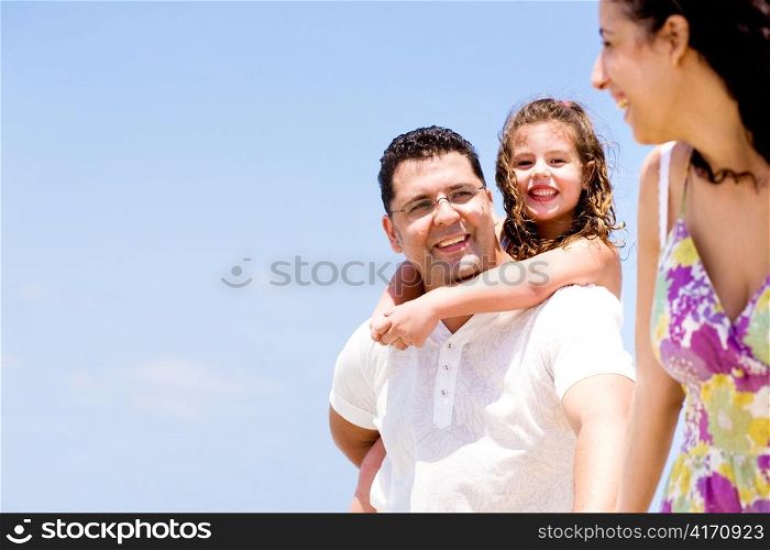 Affectionate couple with daughter looking at camera on the beach