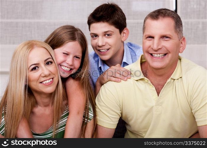 Affectionate family of four smiling at camera and having fun