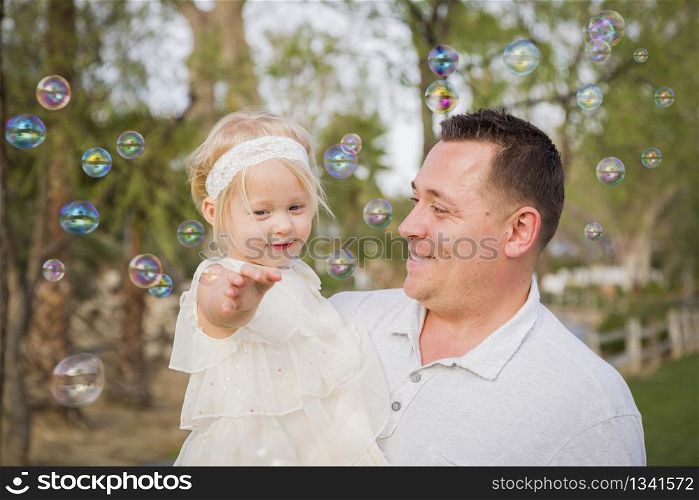 Affectionate Father Holding Cute Baby Girl Enjoying Bubbles Outside at the Park.