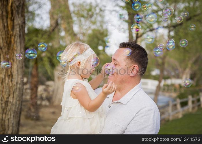 Affectionate Father Holding Cute Baby Girl Enjoying Bubbles Outside at the Park.