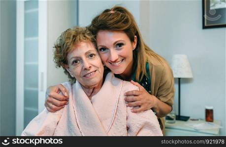 Affectionate female caretaker posing with elderly female patient. Affectionate caretaker posing with elderly patient