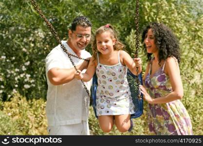 Affectionate parents pushing swing gently