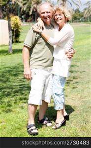 Affectionate senior couple embracing in the park and posing in front of camera