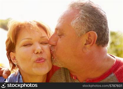 Affectionate Senior Couple Kissing In Garden