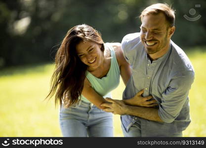 Affectionate young couple having fun on the green grass at the park