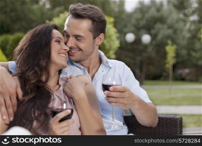 Affectionate young couple having red wine in park