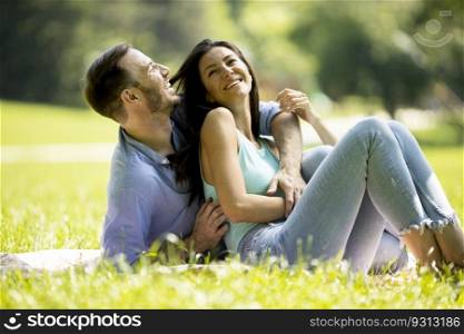 Affectionate young couple sitting on the green grass at the park