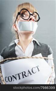 Afraid businesswoman bound by contract terms and conditions with mouth taped shut. Scared woman tied to chair become slave. Business and law concept.. Businesswoman bound by contract with taped mouth.