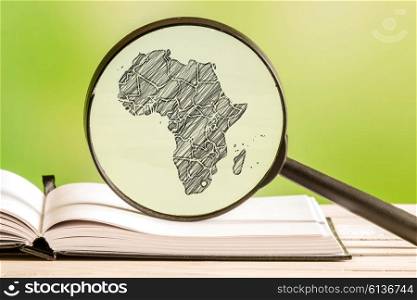Africa information with a pencil drawing of an african map in a magnifying glass