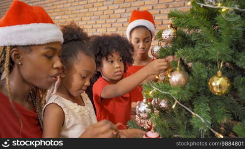 African American black family, women and kid girl daughters hanging socks on Christmas tree on Merry Christmas Eve Xmas Party. Celebration together at home. People lifestyle. Santa Claus.