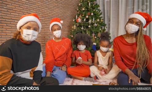 African American black family,women and kid girl daughters with face masks sharing gifts on Merry Christmas Eve Xmas Party. They talking video call online Celebration in covid 19 coronavirus pandemic