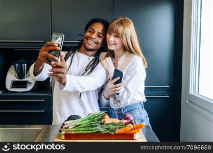 african american boy and white girl making a selfie in the kitchen