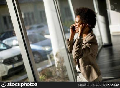 African American business woman using mobile phone by the window in the office on a sunny day
