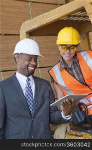 African American businessman and female industrial worker looking at tablet PC