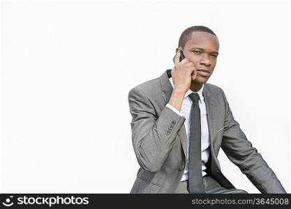 African American businessman conversing on cell phone over white background
