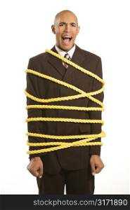 African American businessman screaming wrapped in yellow rope.