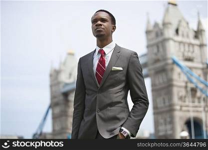 African American businessman standing against London Bridge