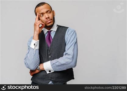 African-American businessmanman making hard decision over grey background.. African-American businessmanman making hard decision over grey background