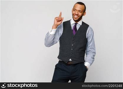 African-American businessmanman showing up by finger over grey background.. African-American businessmanman showing up by finger over grey background