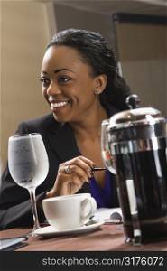 African American businesswoman smiling and sitting at table in restaurant.