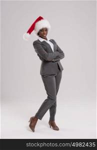 African American businesswoman wearing Santa Claus hat full length portrait on gray background