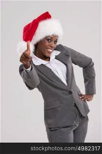 African American businesswoman wearing Santa Claus hat thumbs up portrait on gray background