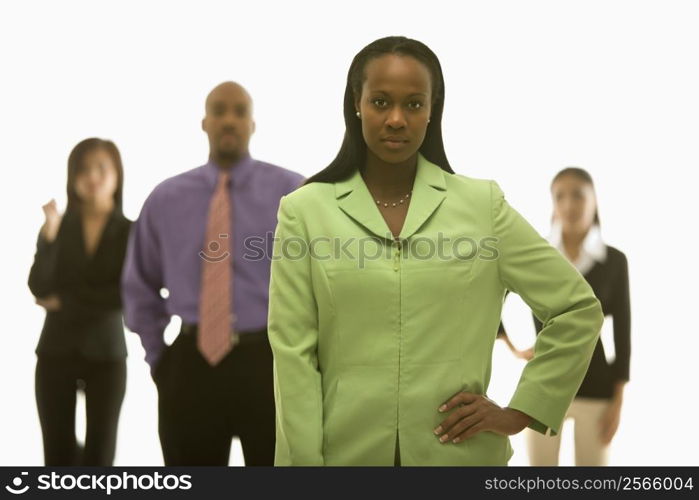 African-American businesswoman with hand on hip with others in background.