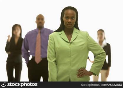 African-American businesswoman with hand on hip with others in background.