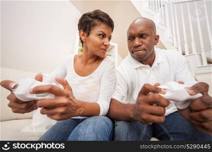 African American couple, man and woman, having fun playing video console games together, looking at each other in intense competition, battle of the sexes.
