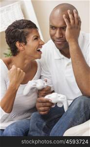 African American couple, man and woman, having fun playing video console games together. The woman has just beaten the man, she is celebrating, he is sad.