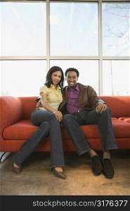 African American couple sitting on couch.