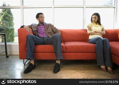 African American couple sitting on couch in dispute.