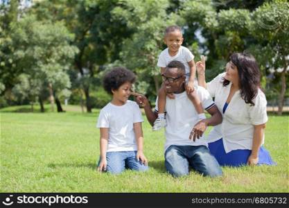 African American family alongside with Asian mum being playful and having good times in the park. African American family alongside with Asian mum being playful and having good times in the park.