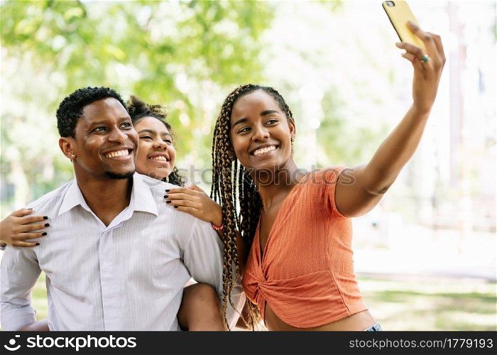 African American family having fun and enjoying a day at the park while taking a selfie together with a mobile phone.