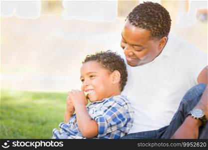 African American Father and Mixed Race Son Eating an Apple in the Park.