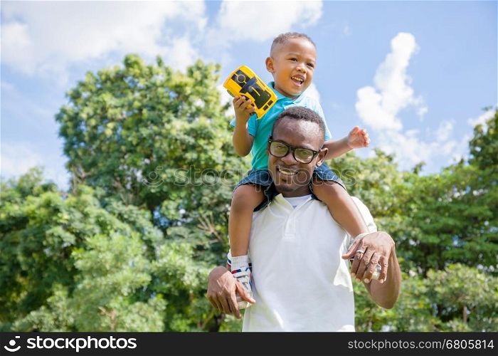 African American father and son piggyback in outdoor park