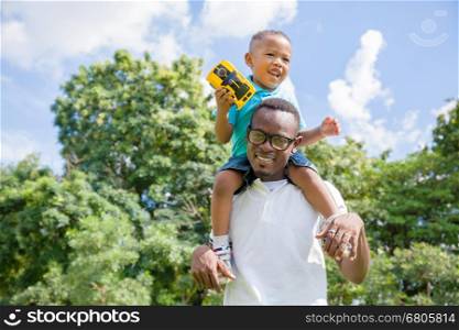 African American father and son piggyback in outdoor park