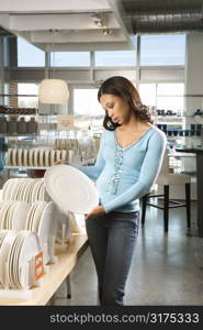 African American female shopping for plates in retail setting.