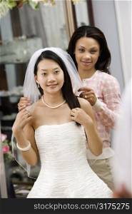 African-American friend holding Asian bride&acute;s veil.