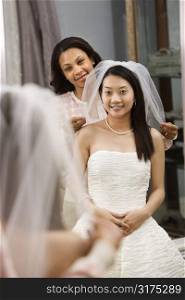 African-American friend holding Asian bride&acute;s veil.